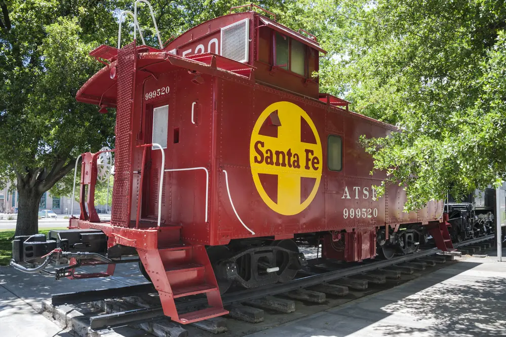 old iron cupola caboose, restored and painted in Santa Fe's Indian red with the yellow Santa Fe cross